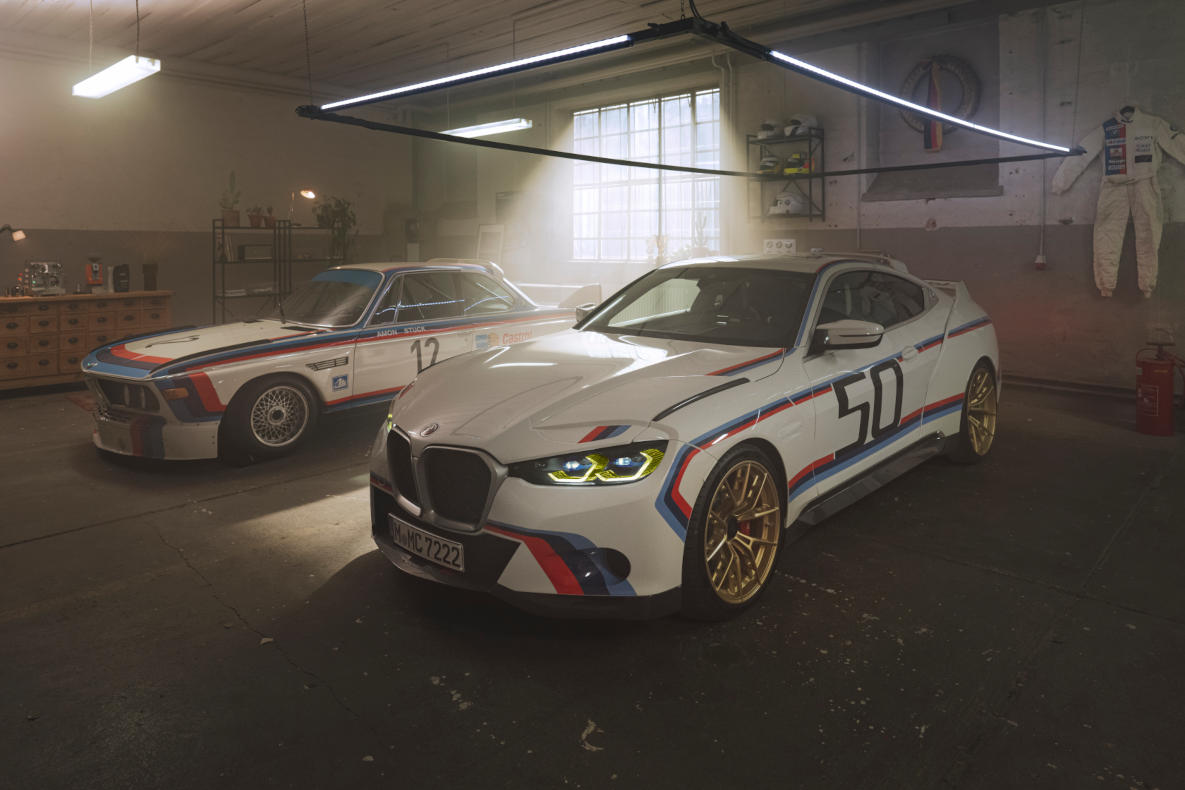 BMW 3.0 CSL from 1972 and 2022 side by side in a garage.