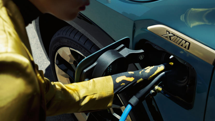 A woman plugs the connector into the charging port of the BMW XM.