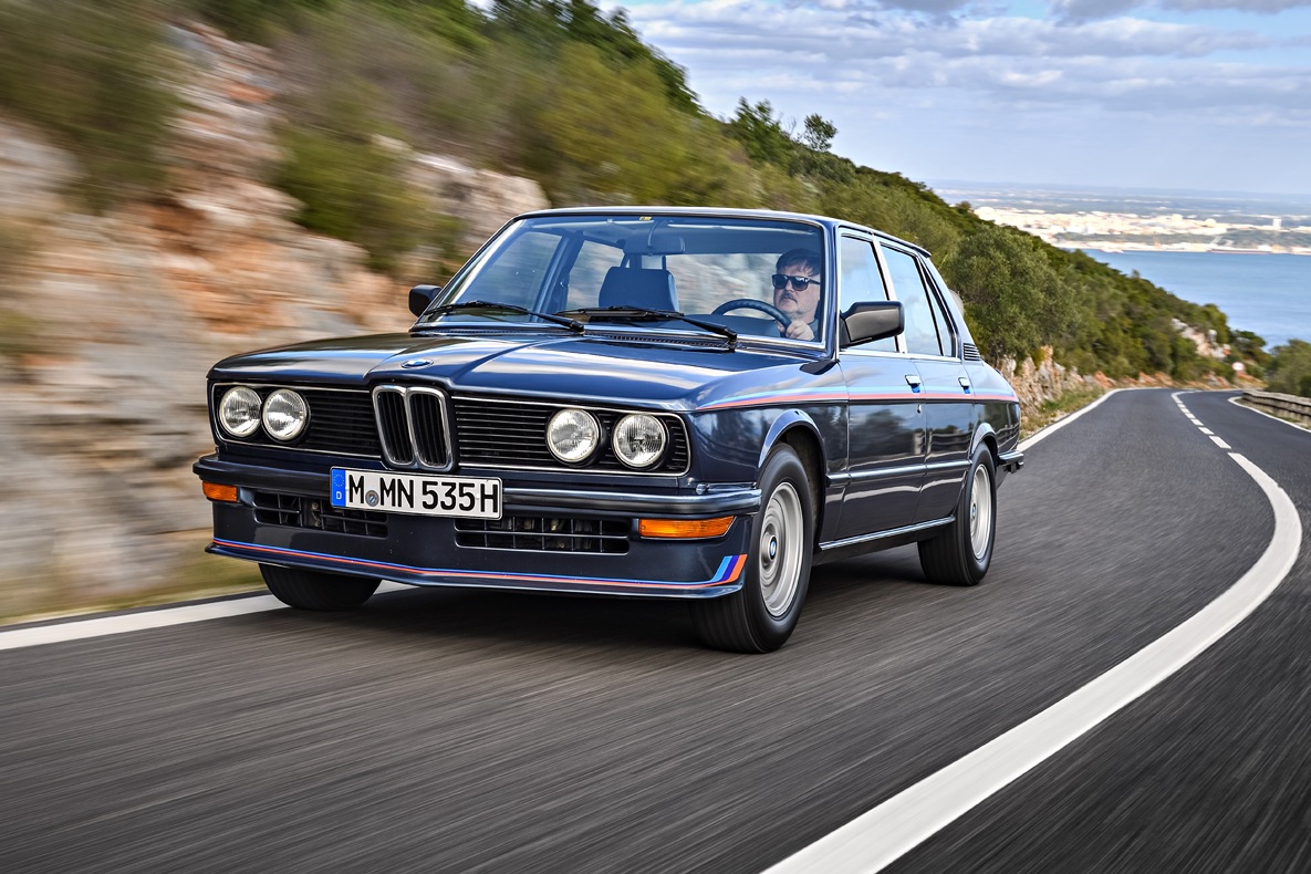 Der BMW E12 M535i fahrend auf der Landstraße.