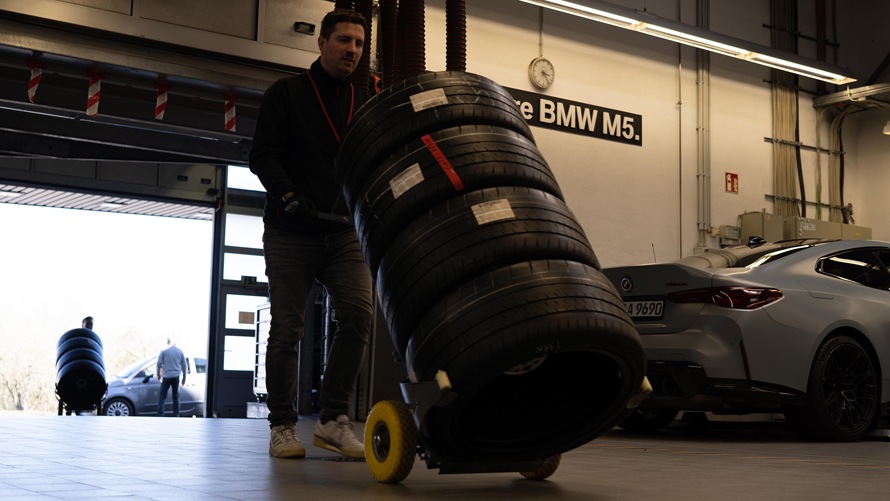 Mechaniker mit Reifenstapel in der Boxengarage
