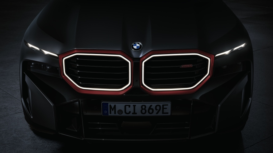 ILLUMINATED M KIDNEY. Catching the eye between the headlights in the centre of the front end is the BMW M kidney grille. The two elements of the grille stand out clearly from the surrounding surfaces. Extending within them are the horizontal grille bars that have become a hallmark feature of the high-performance sports cars from BMW M GmbH, while the double surrounds of the kidneys emphasise their octagonal contours particularly vividly. The outer border of each kidney is Black high-gloss in colour and Toronto Red metallic on the limited-edition variant. The inner surround provides contour lighting in the form of a sharply drawn – and, for the first time, unbroken – light ring. The light array formed by the upper headlight units and the kidney grille’s contour lighting gives the BMW XM Label Red an unmistakable and boldly confident night design.