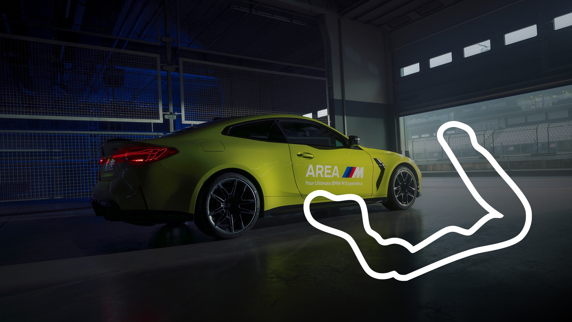 Ein leuchtend gelber BMW M Sportwagen, der in einer Garage oder einem Ausstellungsraum mit blauer Beleuchtung parkt. Das Fahrzeug trägt die Aufschrift 'AREA M' an der Seite, was auf ein BMW M Erlebnis hinweist. Ein weißer Umriss einer Rennstrecke ist auf dem Boden neben dem Fahrzeug projiziert oder angezeigt.