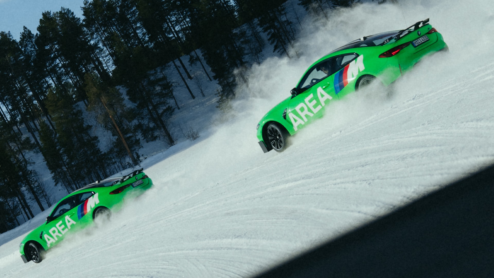 Zwei BMW M grün mit AREA M Beschriftung im Konvoi-Drift im Schnee vor einem Nadelwald