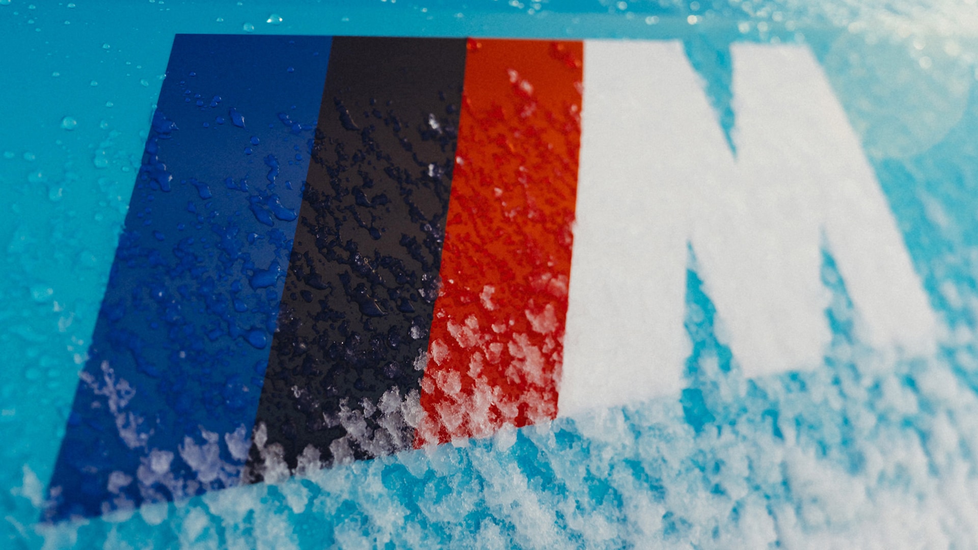 BMW M Logo mit farbigen M Streifen auf schneebedecktem BMW