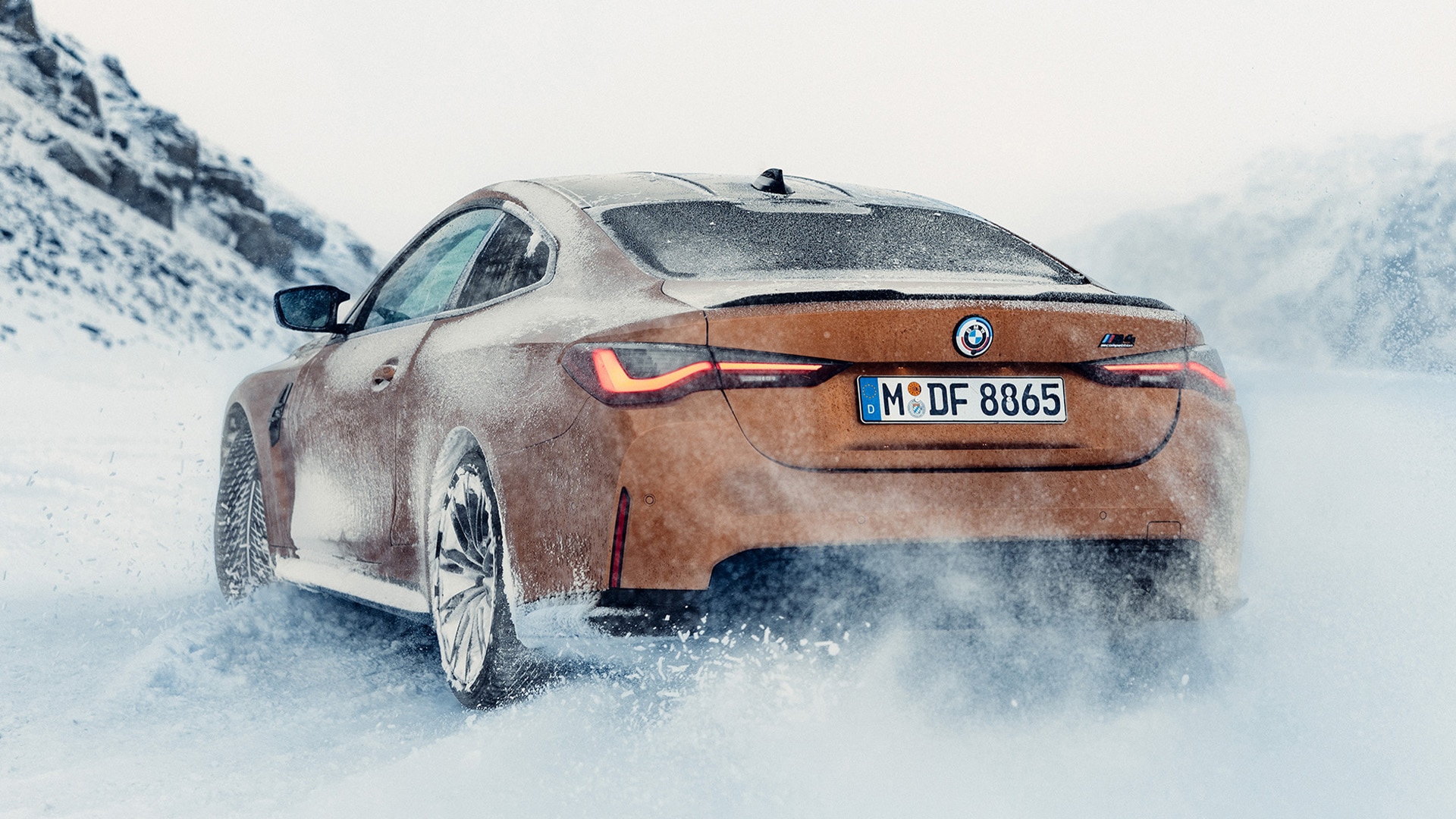 BMW M4 kupferfarben in dreiviertel Heckansicht auf Schnee