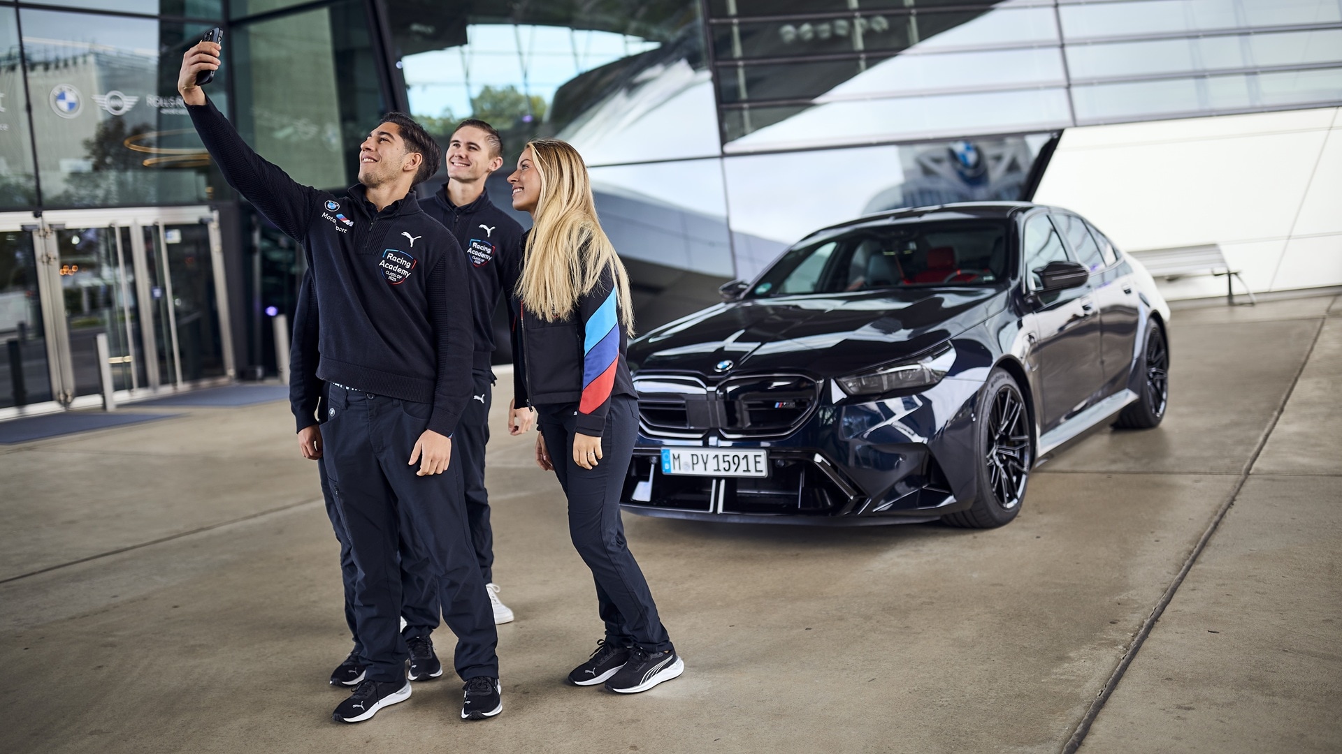 Nerea Martí, Berkay Besler und Matt Million machen ein Selfie mit sich und einem BMW M5.