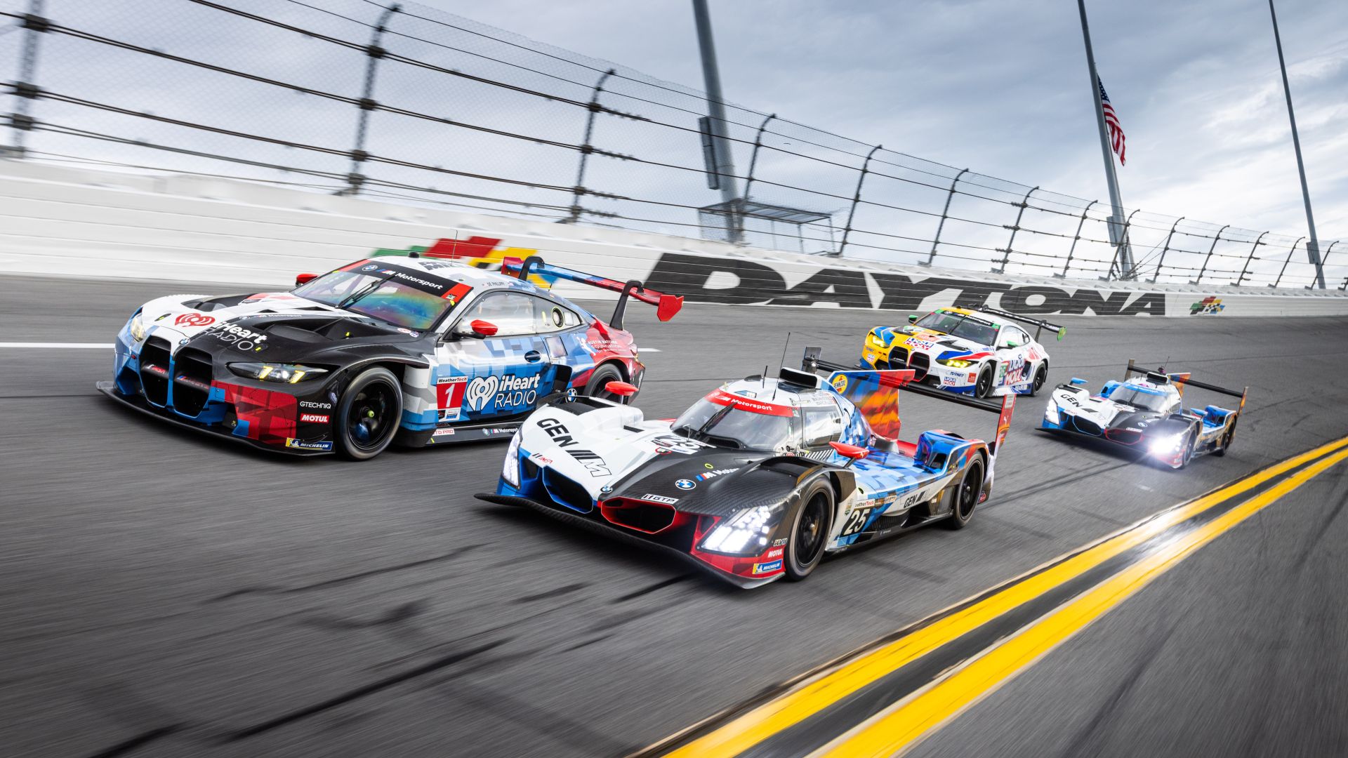 Two BMW M Hybrid V8 and two BMW M4 GT3 EVO on the racetrack at Daytona. 