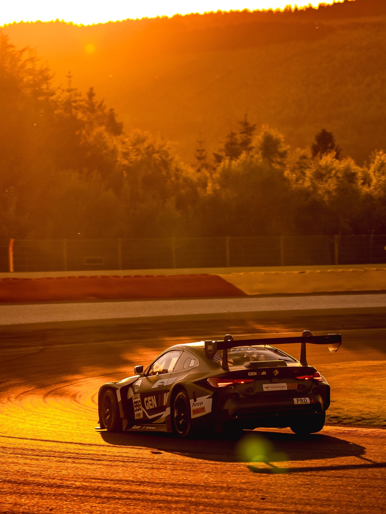 BMW M4 GT3 EVO von Rowe Racing mit der GEN-M-Livery fährt bei Sonnenuntergang auf der Strecke Spa-Francorchamps