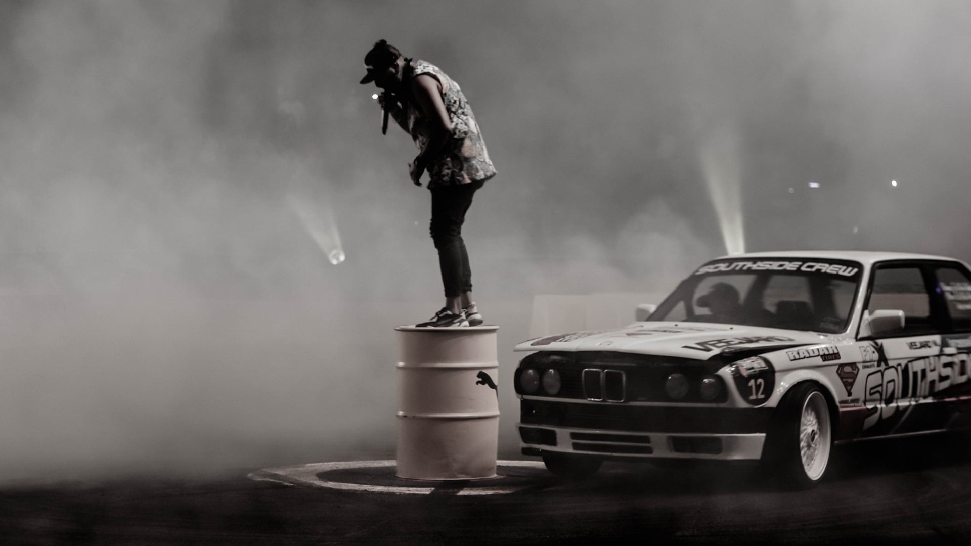 Vic Pardal moderiert ein Spinning-Event, während ein BMW E30 um ihn kreist (spinnt).