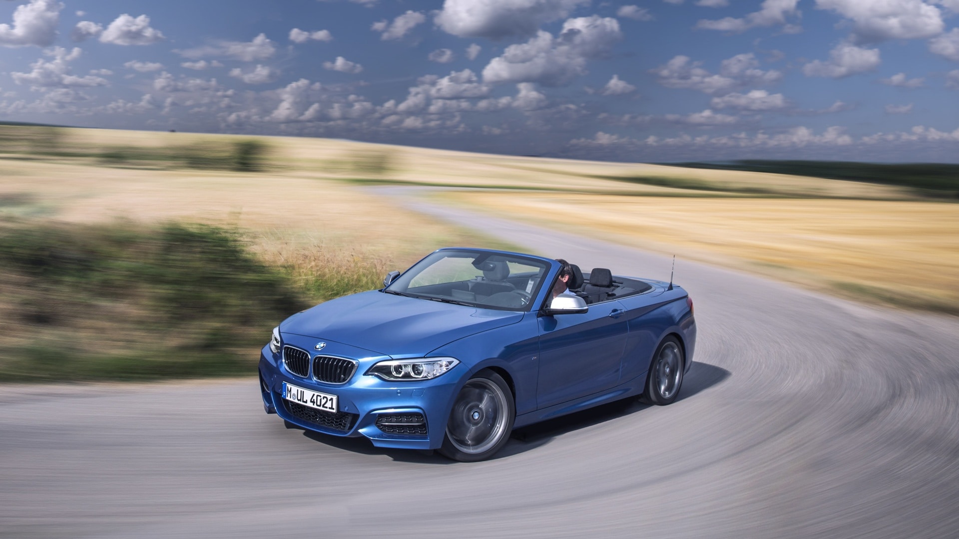BMW M235i Cabrio F23 fährt entlang eines Kornfeldes.