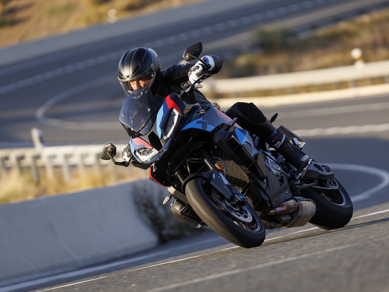 BMW M 1000 XR fährt auf kurviger Landstraße. 