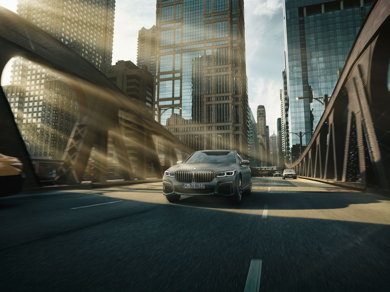 Das Modell-Update vom M760Li xDrive V12 fährt über eine Brücke in einer urbanen Landschaft. 