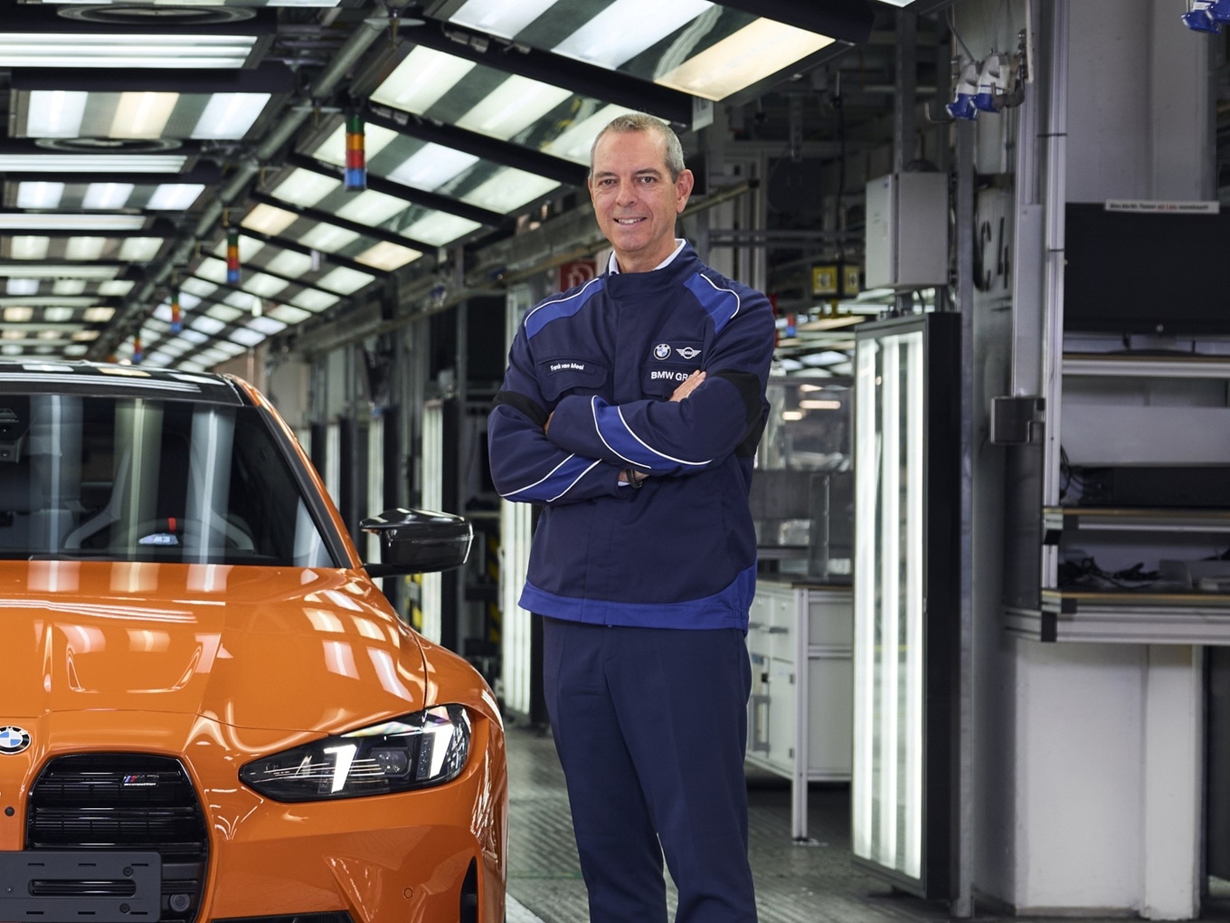 Franciscus van Meel, Geschäftsführer der BMW M GmbH, steht vor dem millionsten BMW M, einem BMW M3 in der Farbe Feuerorange.