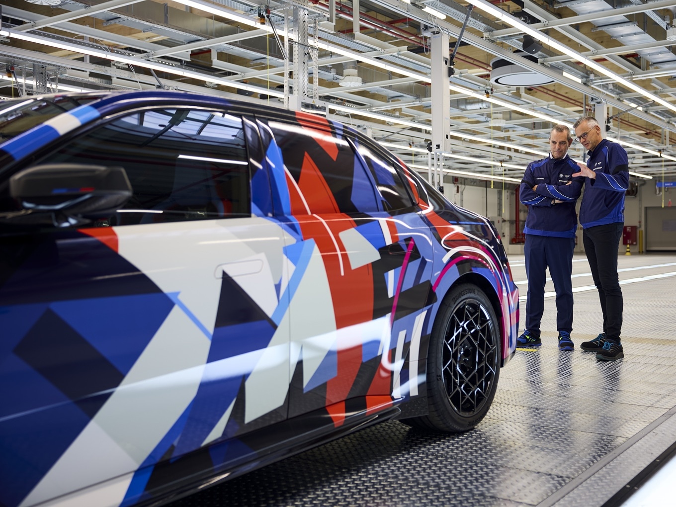 Franciscus van Meel und Peter Weber stehen am Vorserienmodell des vollelektrisierten BMW M3..