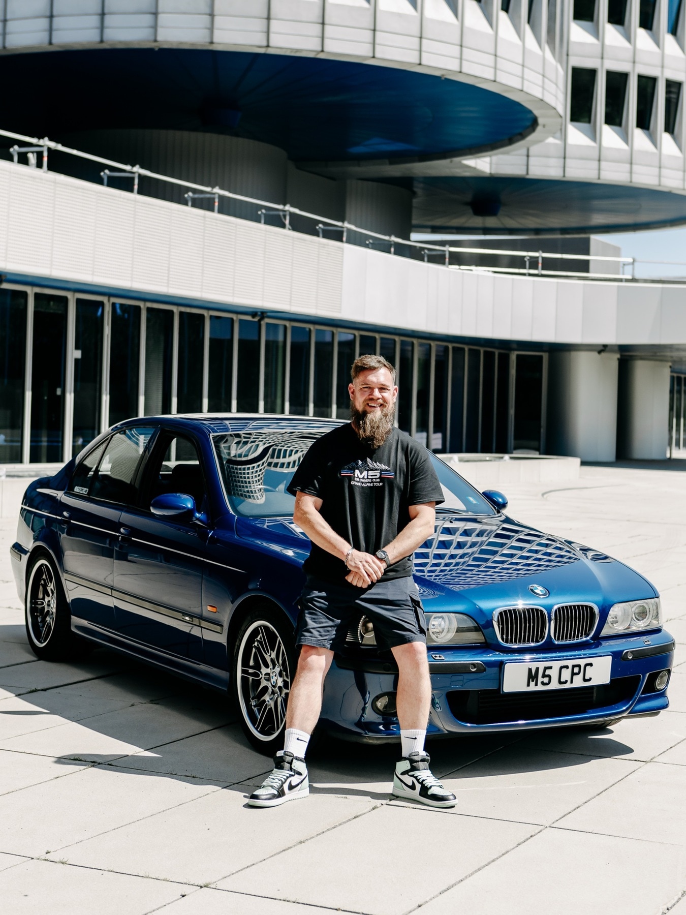 Besitzer mit seinem BMW M5 E39 vor dem Haupteingang des BMW-Gebäudes in München. 