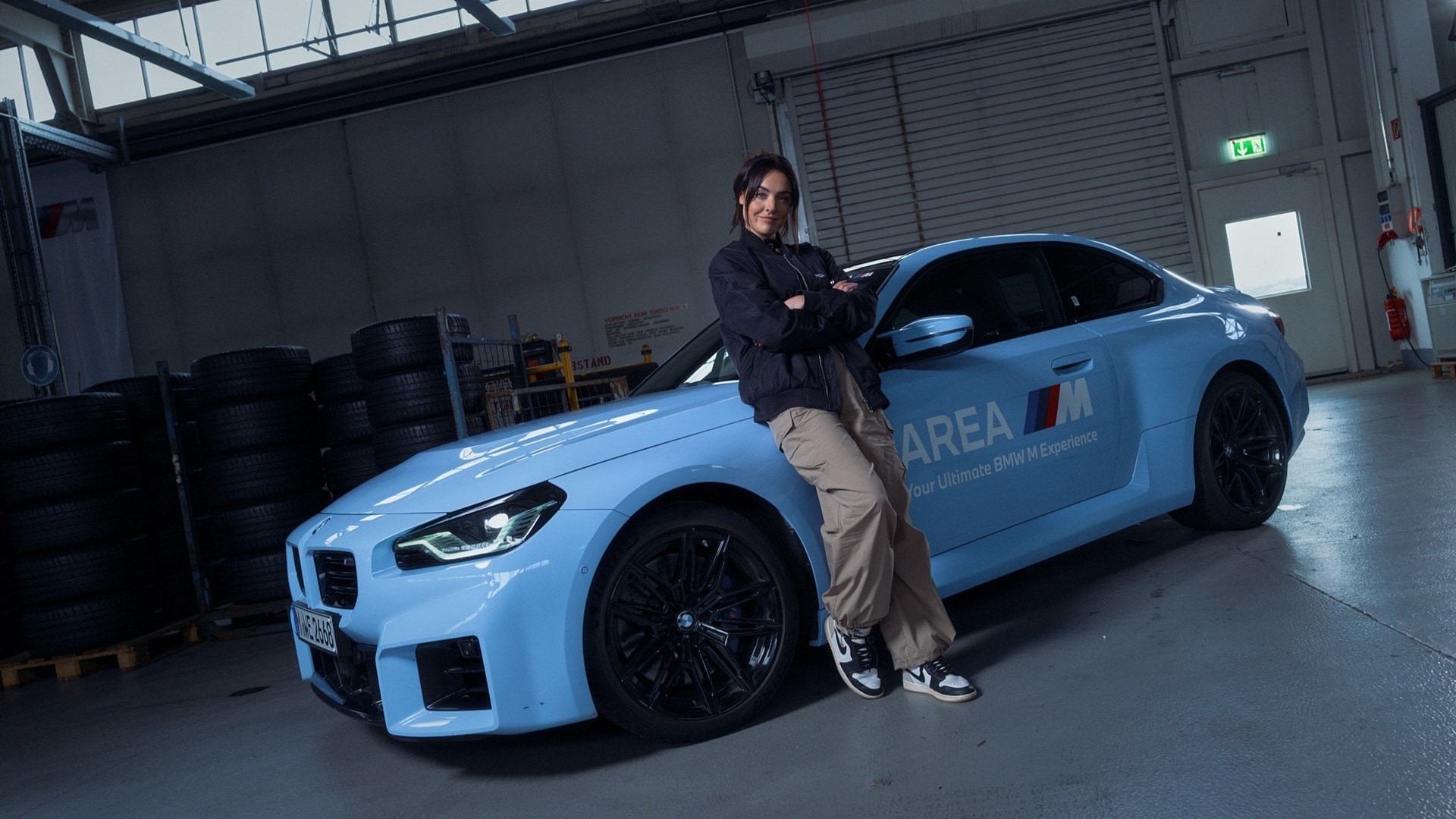 Becky Evans leaning against a BMW M2.