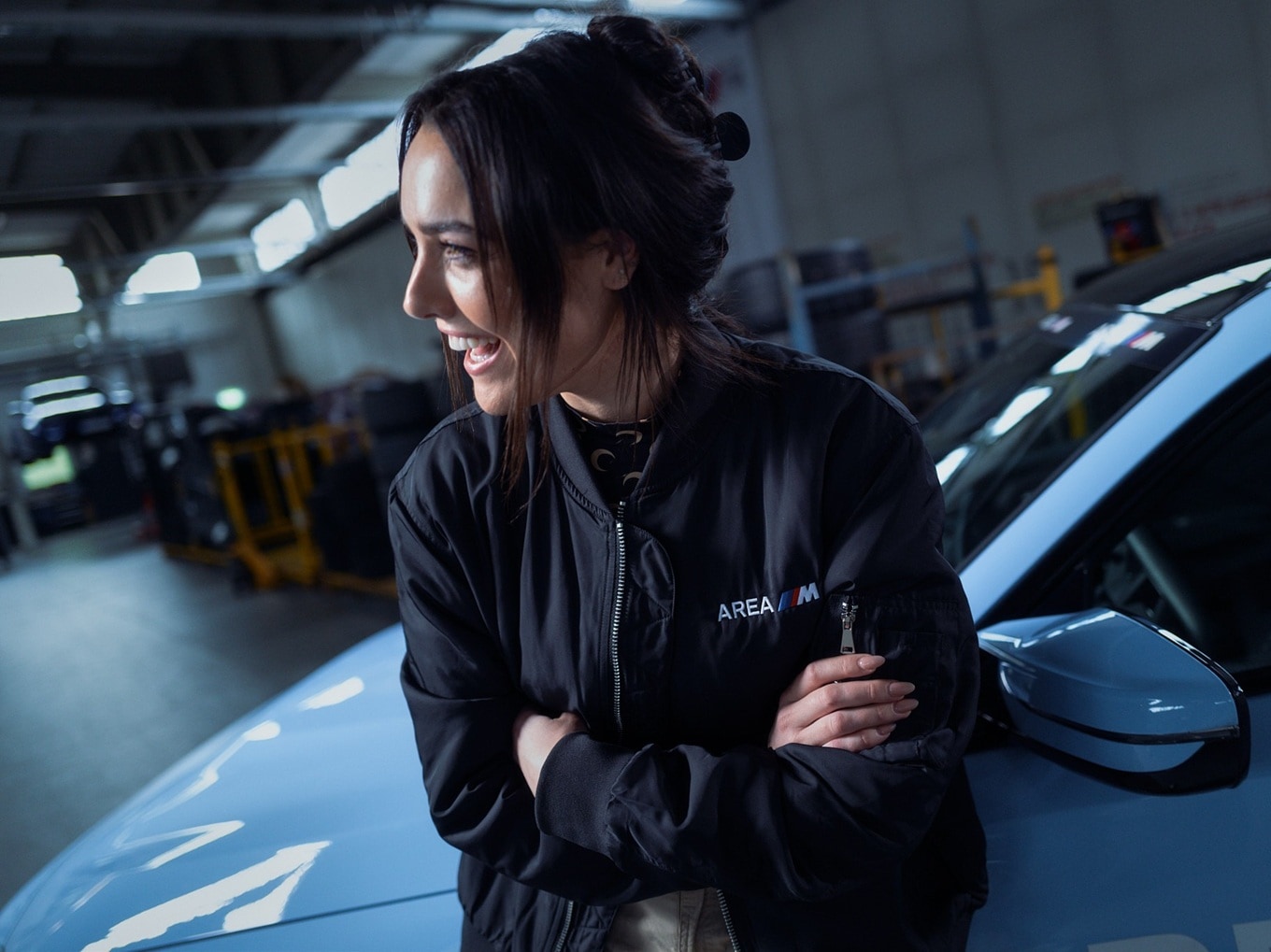Becky Evans leaning against a BMW M2.