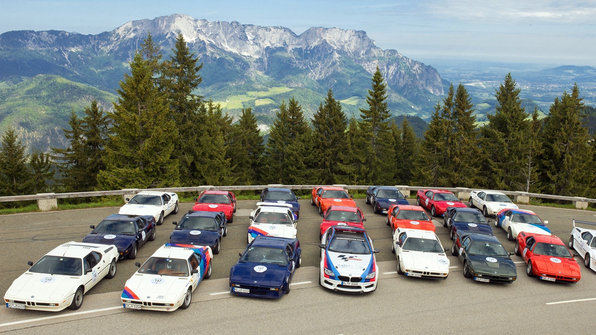 A gathering of BMW M cars before the backdrop of a mountain scenery. 