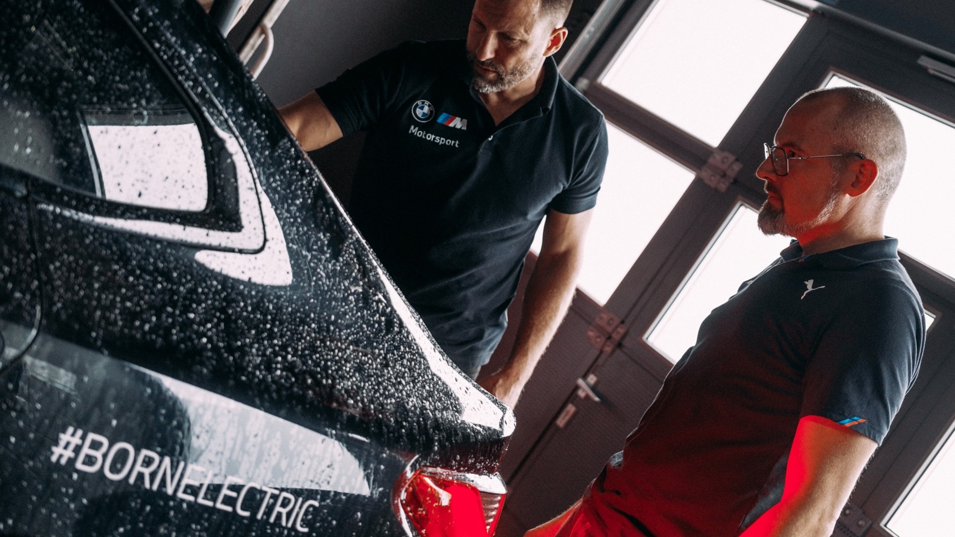 Two BMW M engineers discussing in a workshop for the development of a fully electric BMW M drivetrain.