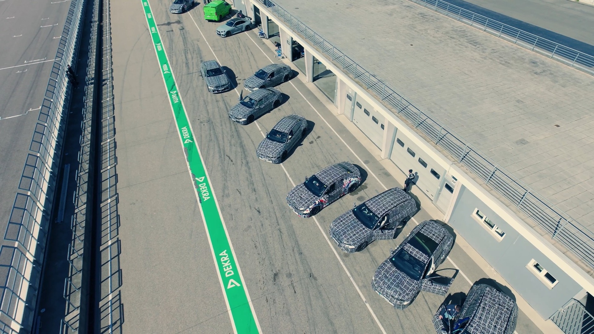 Aerial shot of BMW pre-productionn models, lined up on the paddock of a racetrack.