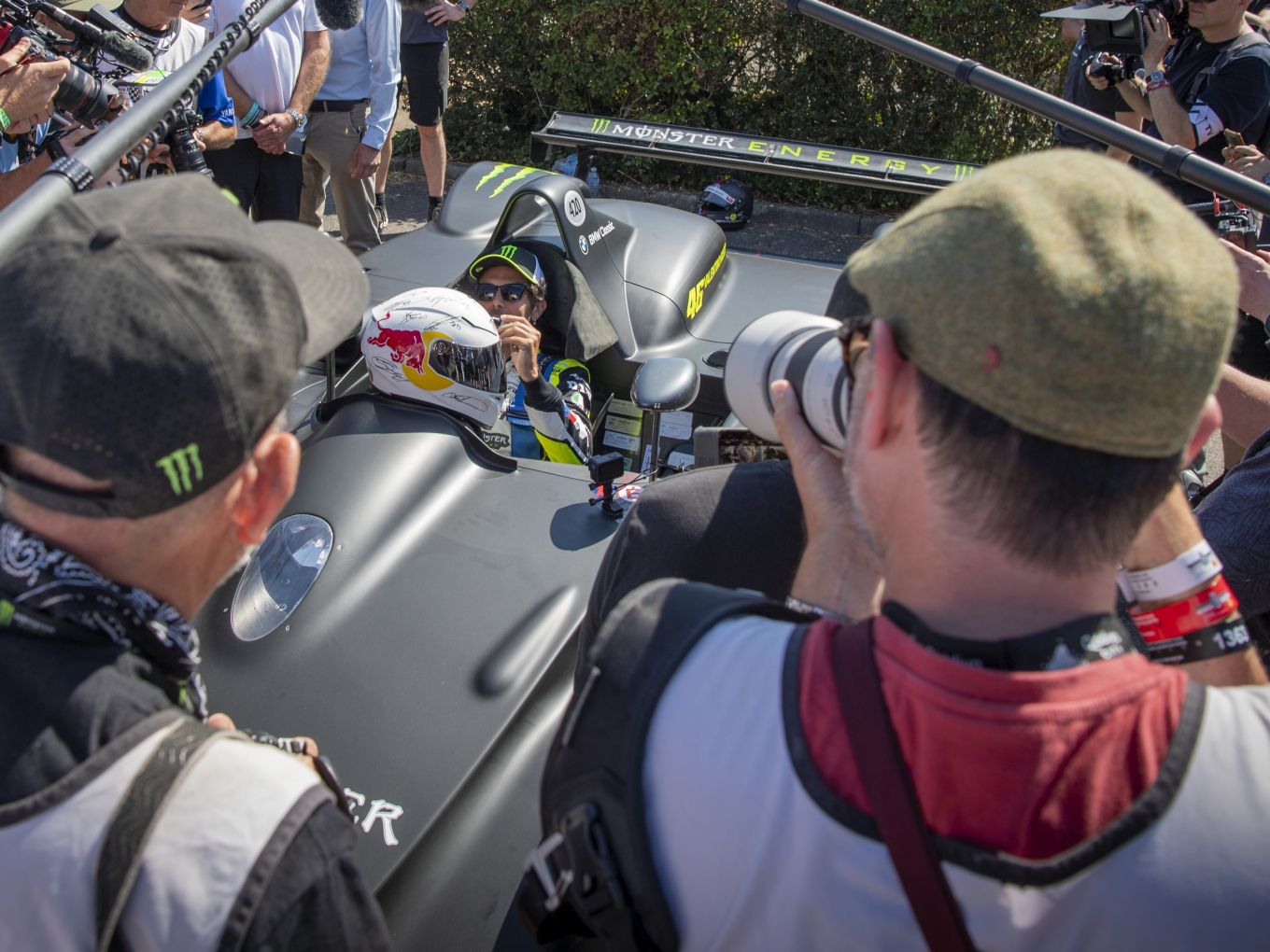 Photographers flocking around Valentino Rossi and the BMW V12 LMR in its matt black livery at Goodwood Festival of Speed 2026.