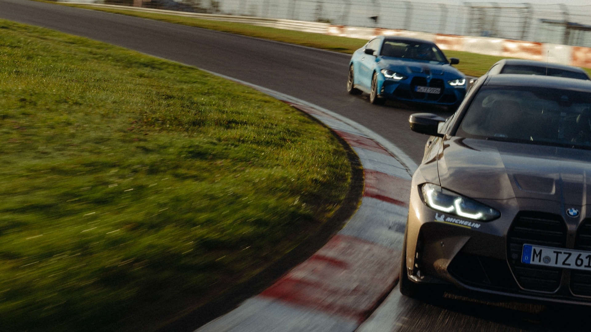 Two BMW M4 racing on a racetrack. 