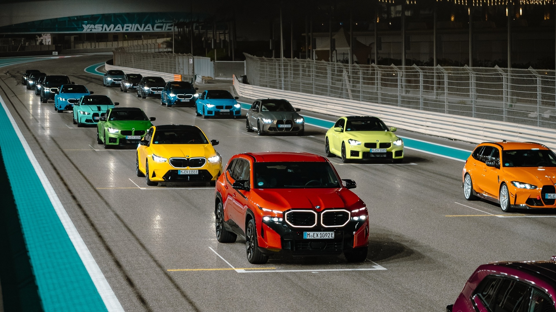 Line-up von über einem Dutzend verschiedener BMW M Modelle, die auf dem Starting Grid der Rennstrecke Yas Marina in Abu Dhabi stehen.