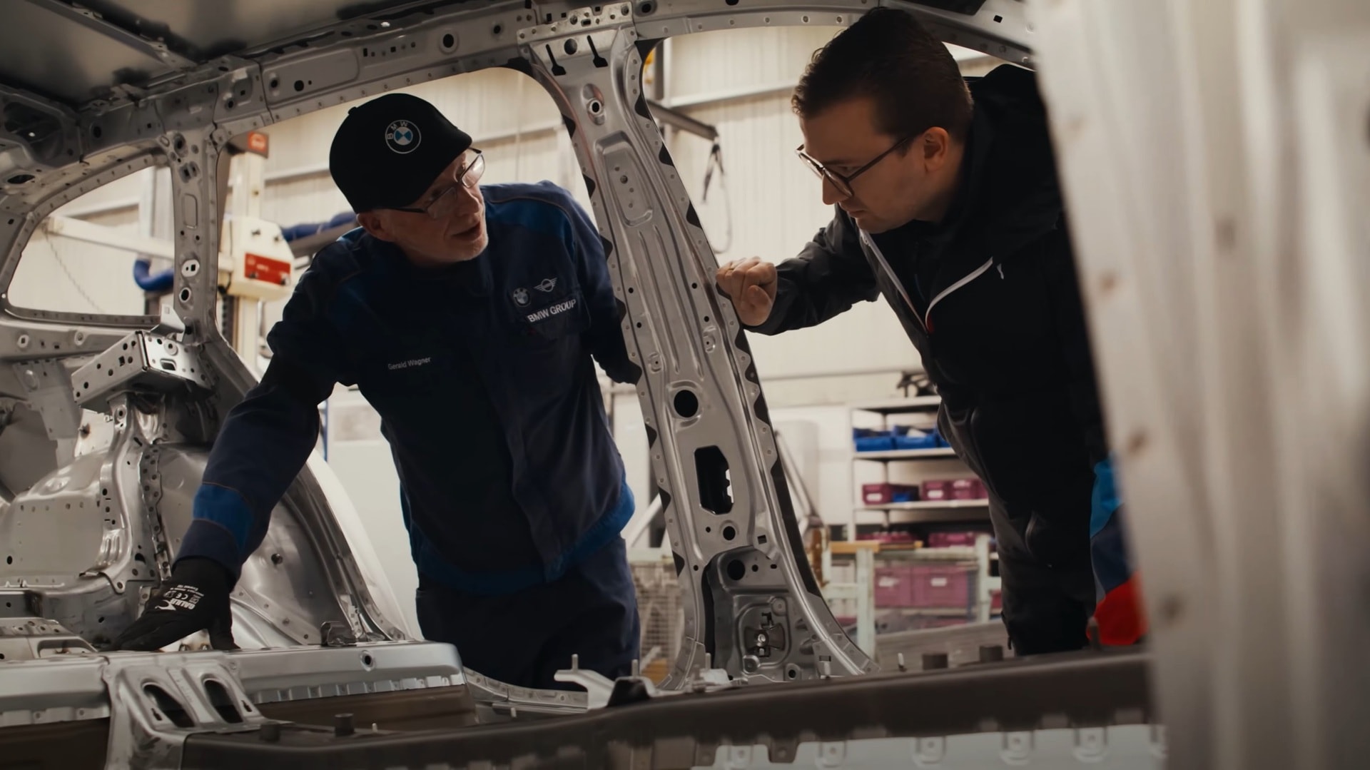 BMW M engineers discussing over a car body shell.